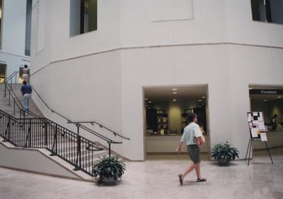 A color photo of the first floor showing the stairs leading up to the second floor and the circulation desk. This photo was taken before it's dedication in 1998. This photo was donated to UARP on May 1, 2003 by Teresa Burgett, Reference Librarian at Young Library