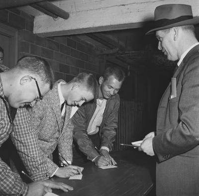 Three men signing forms. Received April 27, 1959 from Public Relations. University of Kentucky Photograph