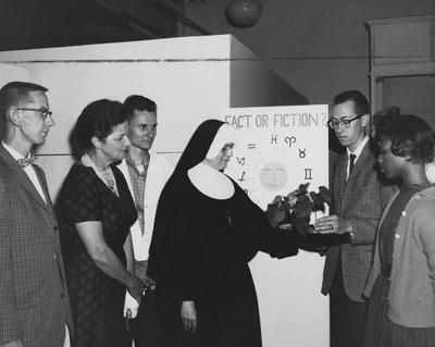 Six people at a science fair looking at a project. Received May 4, 1962 from Public Relations