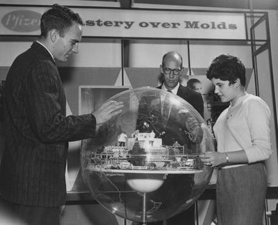 Two men and a woman looking at a model near the Pfizer display at the 1957 Career Carnival. Lexington Herald-Leader photo