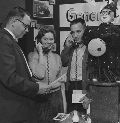 Mrs. Charles Marcus (center) and Charles Marcus (right) are on telephones. Carl Gorhman is on the left. Lexington Herald-Leader photo. Received November 4, 1958 from Public Relations