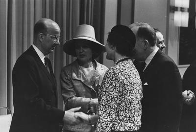 Four people talking one of whom is Rosanel Oswald in large light colored hat