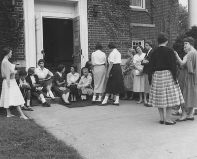 Orientation--unidentified, Ann Emmons, unidentified, and Mary Evelyn are all standing outside waiting for orientation. Received September of 1957 from Public Relations