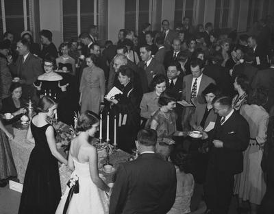 Shot of a tea given in the Fine Arts Building Lounge during Founder's Week. Pouring: Mrs. M. M. White, and Mrs. H. L. Donovan (back to camera). At tea table is Janice Stille (in black). Bald man is Frank J. Prindl, in front of Frank is Sam Morton. Photographer: John B. Kuiper