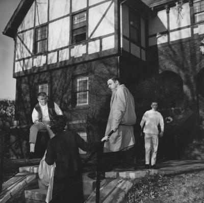 Sigma Nu house with three men in front talking with a woman