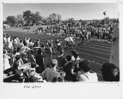 Fraternity members participate in bicycle race; Lambda Chi Alpha and Theta Chi shirts are visible in the crowd. This photo appears first on page 275 in the 1969 Kentuckian