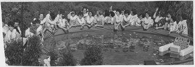 Girls wearing leis, standing around a pool