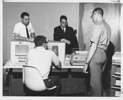 Four unidentified men around a typewriter