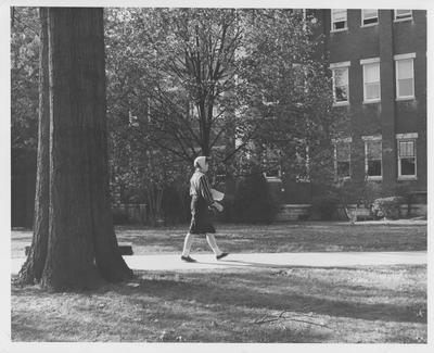 A female student walking between classes. Received December 11, 1961 from Public Relations