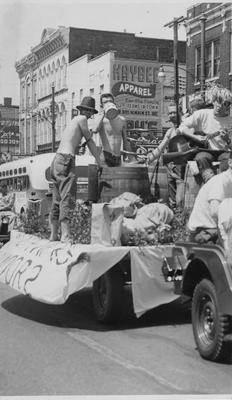 Homecoming Parade, people dressed as Hillbilly's with moonshine in a barrel, going down Main Street in downtown Lexington. Lexington Herald-Leader staff photo. Received May 13, 1959 from Public Relations