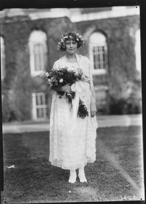 A young woman in a white dress, holding a bouquet of roses, wearing a flower headdress