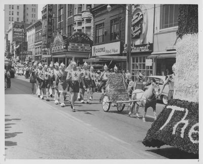 Pi Kappa Alpha's Praetorian Guard marching down Main Street past Skuller's Jewelers, in the May Day parade. This image appears fifth on page 355 in the 1957 Kentuckian. Received August 17, 1957 from Public Relations