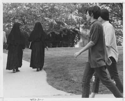 Two unidentified students and two nuns are walking on campus; This photo is in the 1969 Kentuckian on page 30 and 31, image number 1