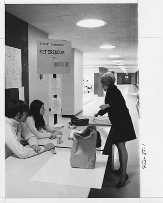 An unidentified student is voting on forced housing and two unidentified students are seated at a table with the Referendum on housing, which was sponsered by the Student Government; This photo is in the 1969 Kentuckian on page 85, image number 1