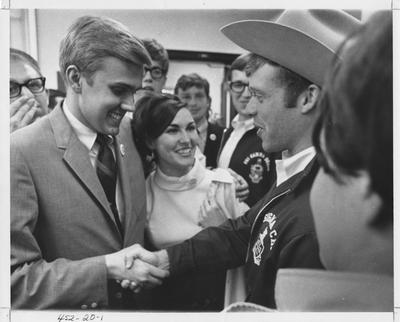 Tim Futrell (left) shaking hands with an unidentified Sigma Chi fraternity member and unidentified students watching; Tim Futrell is the president of the Student Government at the University of Kentucky in 1969; This photo is in the 1969 Kentuckian on page 20, picture number 1