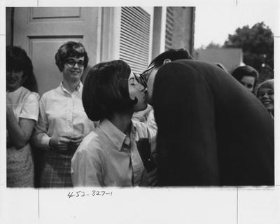 Couple kissing in front of a crowd at the Zeta Tau Alpha house; This image is in the 1969 Kentuckian on page 327, image 29