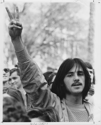 Male student flashes a peace sign during a protest; This image is in the 1969 Kentuckian on page 285, image 1