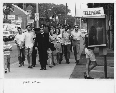 On the day that Eugene McCarthy’s bid for the 1968 Democratic presidential nomination at the convention was unsuccessful, students march from the McCarthy campaign headquarters on Woodland Avenue to Euclid Avenue to the University of Kentucky Student Center in a “funeral” procession to mourn the passing of democracy and the Democratic party.  Marchers carry a coffin and wear black arm bands and upside-down McCarthy buttons.  The Reverend Gary Pritchard leads the march and gives a sermon.  Photo is in the 1969 Kentuckian on page 24. See the Kentucky Kernel article from 1968 August 30