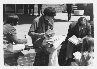 Students reading materials in front of the Student Center