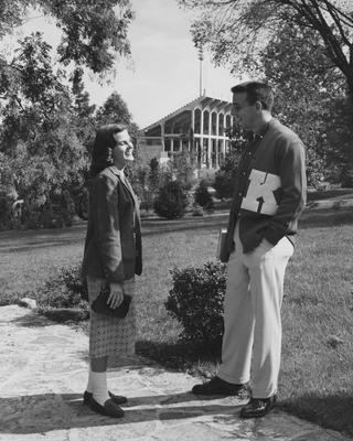 Male and female student talking; In the background is McLean Stadium, which was located on Stoll Field
