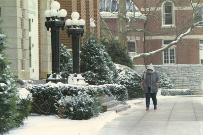 Student walks in front of the Administration Building on a snowy day; the Gillis Building can be seen in the background; 1997 calendar picture; Photographer: Nigel Scott