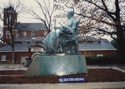 A side view of the James K. Patterson statue near the Patterson Office Tower and the Administration Building; Buell Armory is in the background