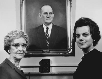 Two women standing in front of Foster portrait