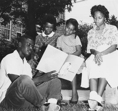 A man reads to three children from a pamphlet called 