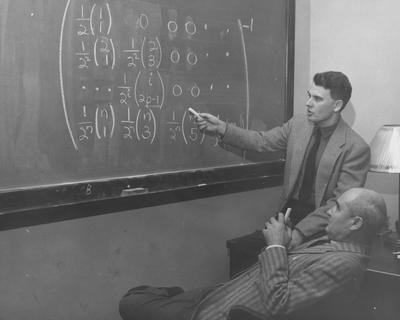 Dr. V. F. Cowling and Dr. J. C. Eaves working on a Math problem at the blackboard