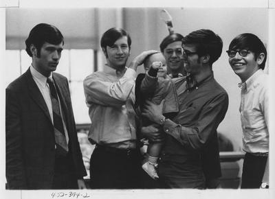 Kernel staff members with a baby; This image is in the 1969 Kentuckian on page 394, image 2