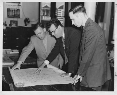 Men studying a map of Harrison County in Kentucky concerning the school system and locations