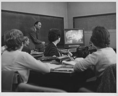 Education students watch closed circuit television as part of an experiment testing the feasibility of using television to observe classroom proceedings; Dr. Leonard Ravitz, associate professor of education and his class observe a class at the University School, a school modeled on the educational philosophy of Dewey