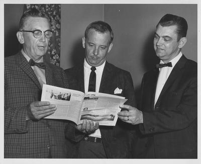 Education Faculty; From left to right: Lyman Ginger, Robinson, and James Moore; looking at a newsletter