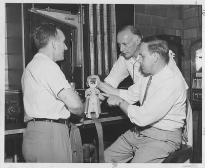 Men overlook engineering equipment; Dr. Karl Lange (center), O. W. Stewart? (right), with an unidentified man