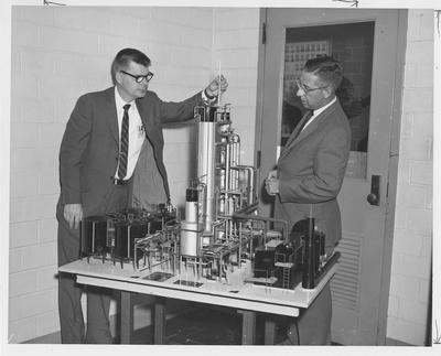 Chemical Engineering professors inspect a scale model of a detergent intermediates plant; This model was given to the department by Proctor & Gamble for use in senior design courses