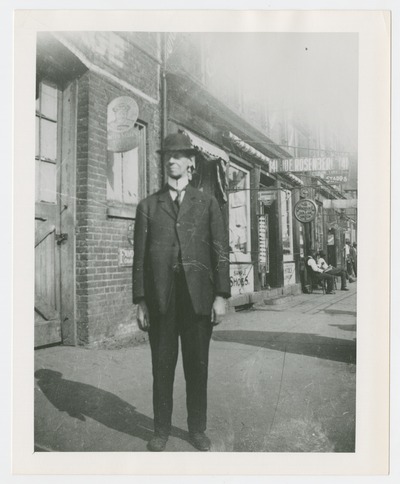Unidentified man on sidewalk in front of shops
