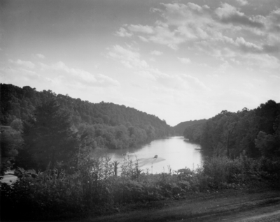 A view of a river with trees on each side and a motor boat in the water