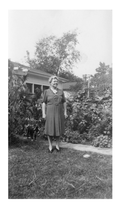 An unidentified woman standing in a yard.  Handwritten on verso, 