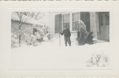 man outside in snow with shovel in front of house
