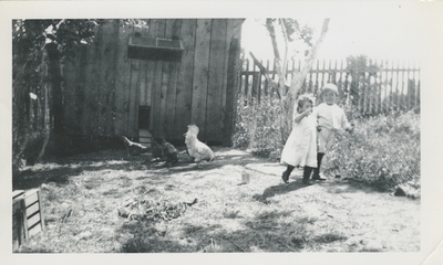 two children outside with chickens