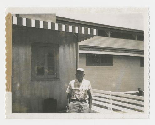 Man standing in front of building and fence, Joyland Park