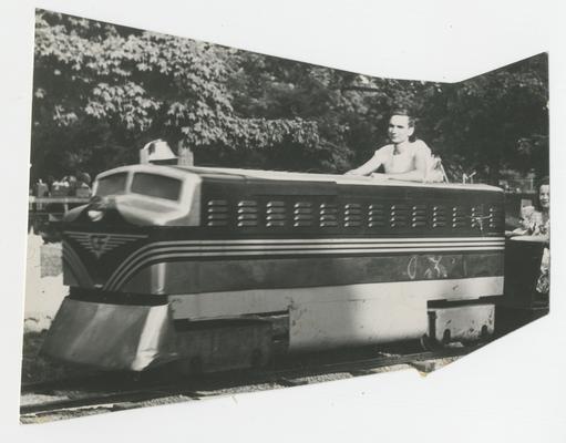 Person sitting in a small train car, amusement attraction, Joyland Park - stamped on back PHOTO BY  AUG 23 1948 HERALD-LEADER