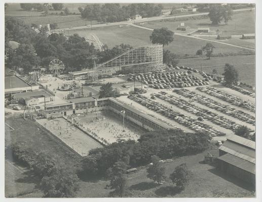 Aerial view of Joyland Park with roller coaster and other amusement attractions and parking lot with cars, Joyland Park -stamped on back of photograph Battaile's Portrait and Bridal Studio 429 West Second St. Lexington 7, Ky