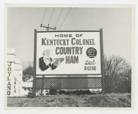 Home of Kentucky Colonel Country Ham Dial 3-1250, sign in ground with man eating ham on it, Joyland Park; advertisement