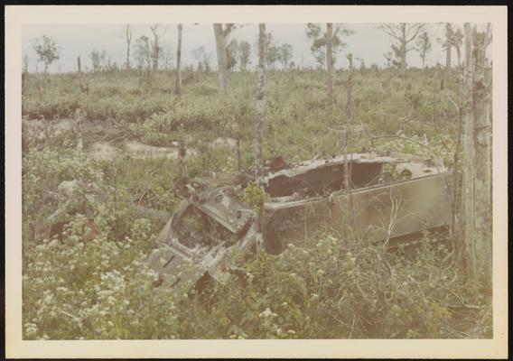 Remains of an armored personnel carrier after it is hit by an RPG, surrounded by remains of jungle after agent orange
