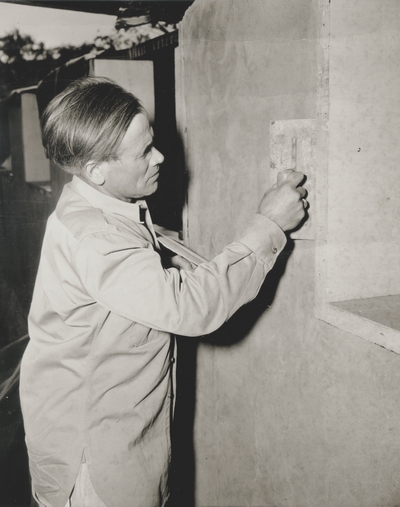 John Jacob Niles applying plaster to rammed-earth walls; Boot Hill Farm