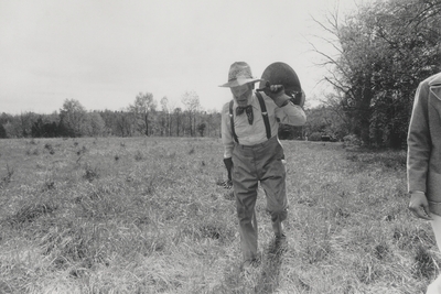 John Jacob Niles carrying a coal bucket through a field; Boot Hill Farm; Kerby Smith