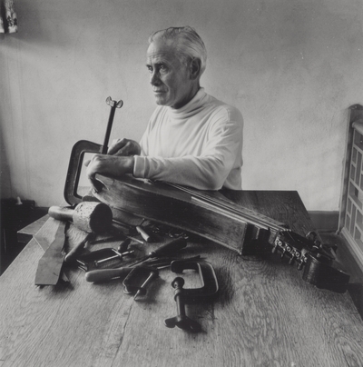 John Jacob Niles repairing a dulcimer at dining room table; Boot Hill Farm; Van Coke