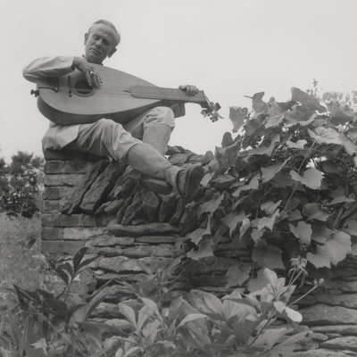 John Jacob Niles seated with dulcimer on a stone wall; Boot Hill Farm; Van Coke
