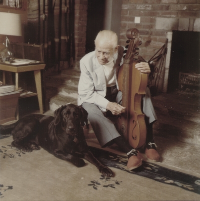 John Jacob Niles with dog, Rosie, in front of fireplace; Boot Hill Farm